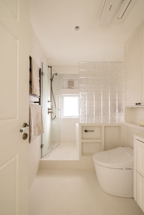 Minimalist modern bathroom design by MAD Studio featuring sleek glass shower, elegant bronze fixtures, and natural colour palette. Contemporary bathroom interiors by top interior design firm highlighting smart use of space and luxury elements. Perfect blend of style and function for home renovation inspiration.
