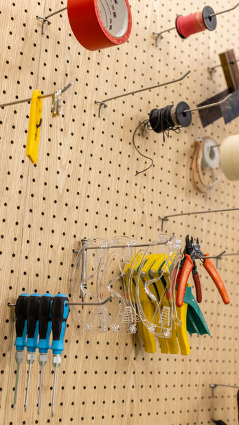 Innovation Hub, VSA, Commercial Interior Design
Interior design workspace featuring a well-organized pegboard with various tools including pliers, screwdrivers, and safety goggles. Efficient studio setup for creative professionals at MAD Studio.
