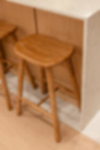 Wooden bar stool beside a light wood counter in a kitchen setting. The stool's smooth finish and natural tones add warmth.