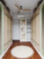 Stylish walk in closet with wood cabinets, geometric floor, and round rug. Ceiling fan contrasts with textured walls, offering a serene ambiance.
