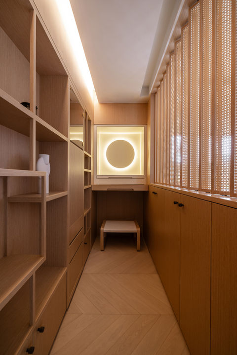 Sleek modern interior design by MAD Studio showcasing minimalist wooden cabinetry and ambient lighting in a luxury walk-in closet, emphasizing contemporary home decor and space optimization.