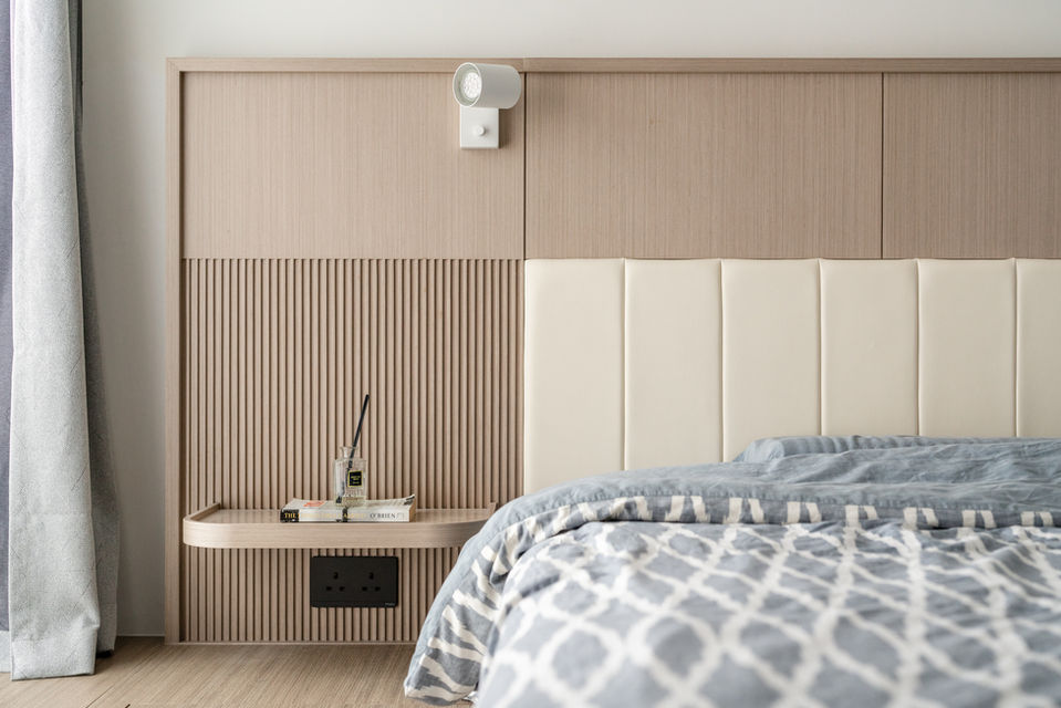 Modern bedroom interior design featuring a minimalist wooden headboard with vertical grooves, integrated bedside shelf, and soft ambient lighting. Elegant gray and white bedding adds a touch of luxury. Perfect blend of functionality and aesthetics.